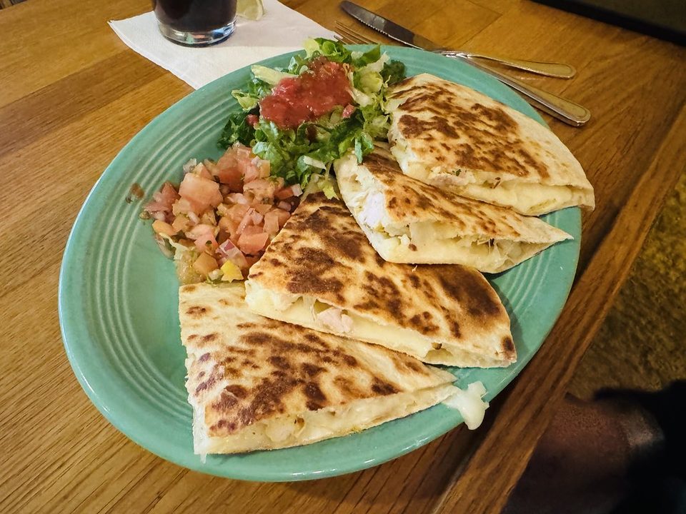 Golden grilled quesadilla wedges on a green plate with fresh salsa salad