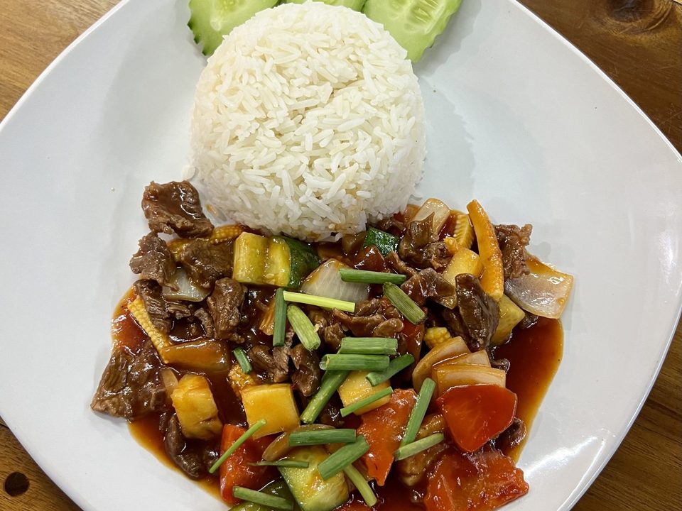 Glazed beef stir-fry with vegetables beside a mound of white rice and cucumber slices